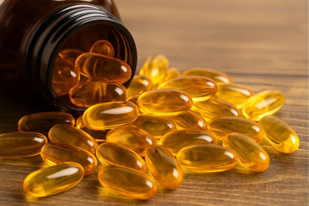 fish oil bottle with softgel capsules spilling onto a wooden surface, highlighting the natural look and benefits of omega-3 supplements.