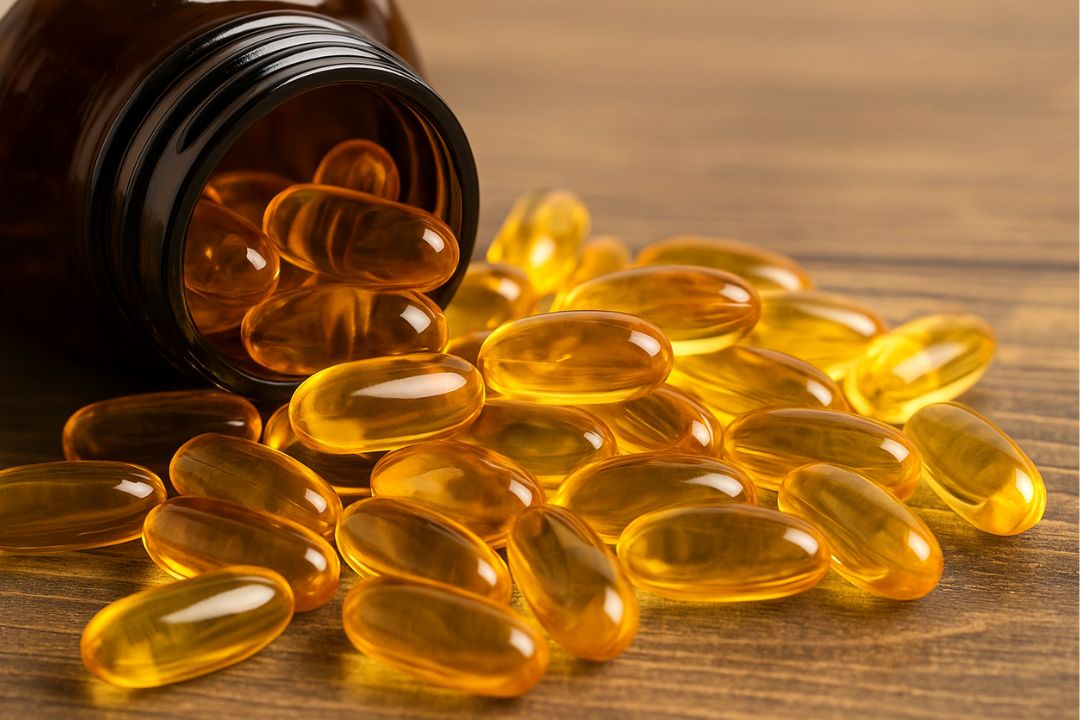 fish oil bottle with softgel capsules spilling onto a wooden surface, highlighting the natural look and benefits of omega-3 supplements.