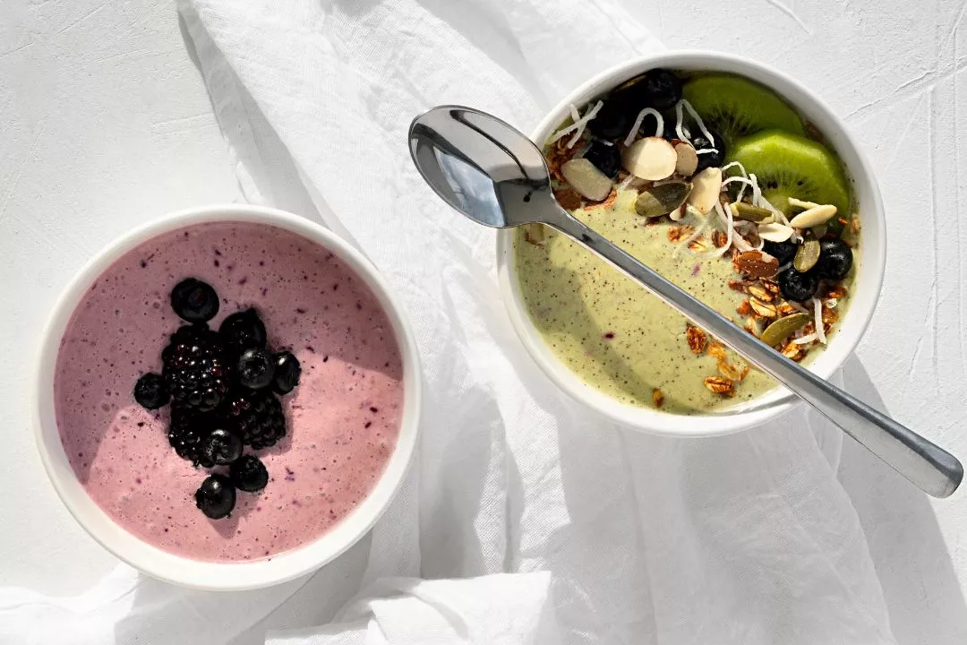 Two colourful smoothie bowls topped with fruit and seeds, showcasing an easy collagen breakfast recipe using X50 Collagen Protein Water Me Muscle Nutrition.